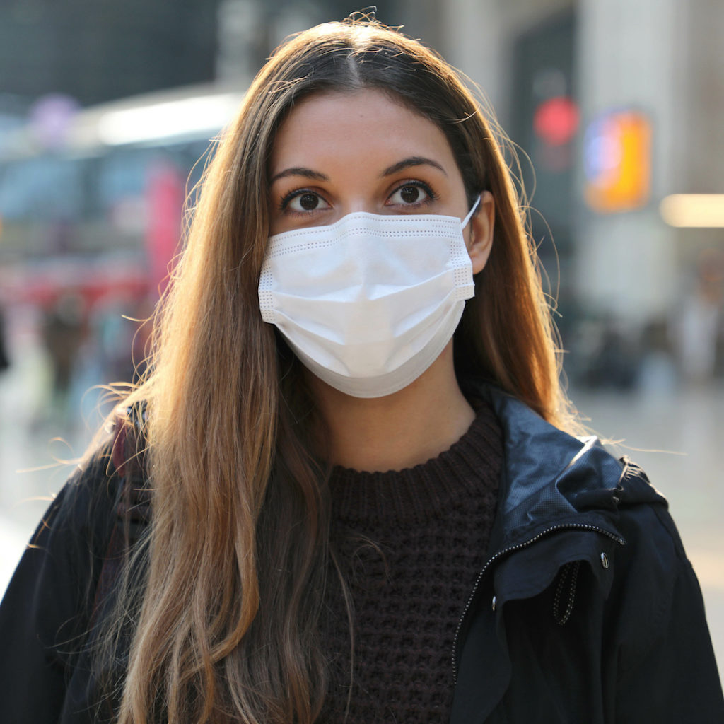 Portrait of young woman wearing surgical mask at train station